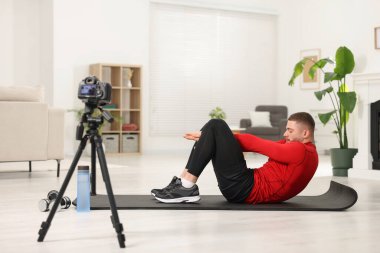 Trainer recording workout on camera at home