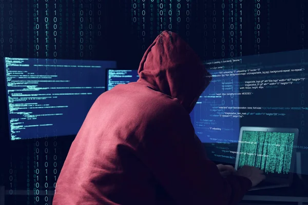 网络攻击 匿名黑客与笔记本电脑和监视器在深蓝色背景下工作 他周围的二进制代码 — 图库照片