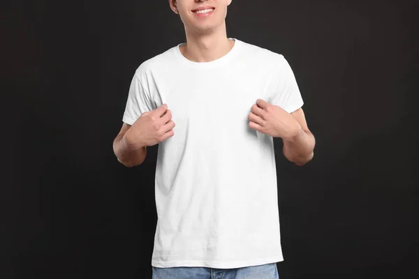 男の黒の背景に白いTシャツを着て クローズアップ デザインのためのモックアップ — ストック写真