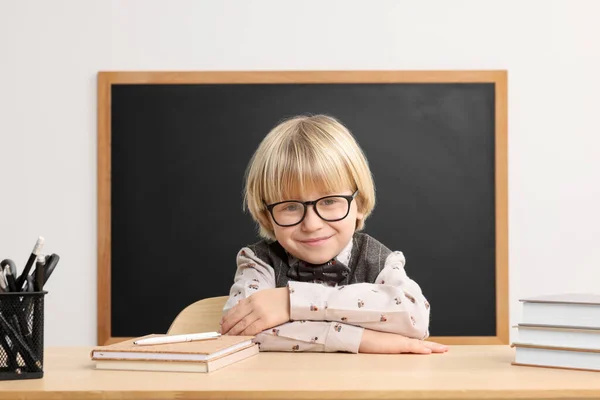 幸せな小さな学校の子供が机の上に座っている教室で黒板の近くの本 — ストック写真