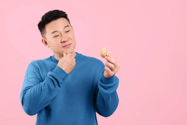 Aziatische Man Met Smakelijk Gelukskoekje Met Voorspelling Roze Achtergrond Ruimte — Stockfoto