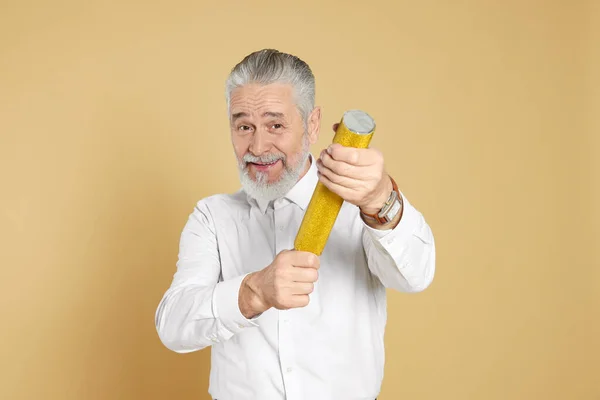 Man with party popper on beige background