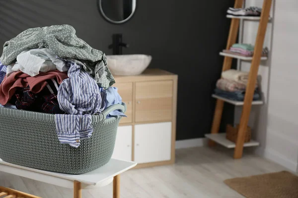 stock image Laundry basket filled with clothes on table in bathroom. Space for text