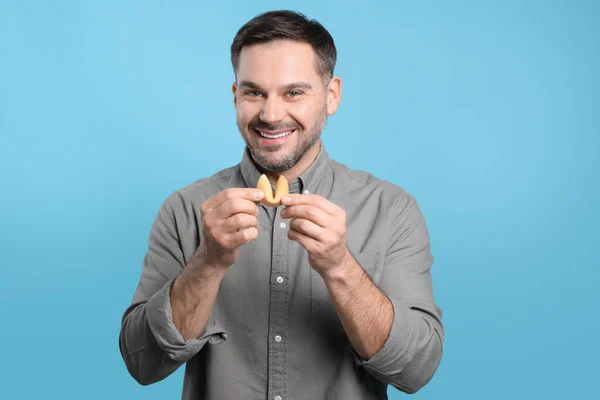 Ευτυχισμένος Άνθρωπος Κρατώντας Νόστιμο Μπισκότο Τύχης Πρόβλεψη Γαλάζιο Φόντο — Φωτογραφία Αρχείου