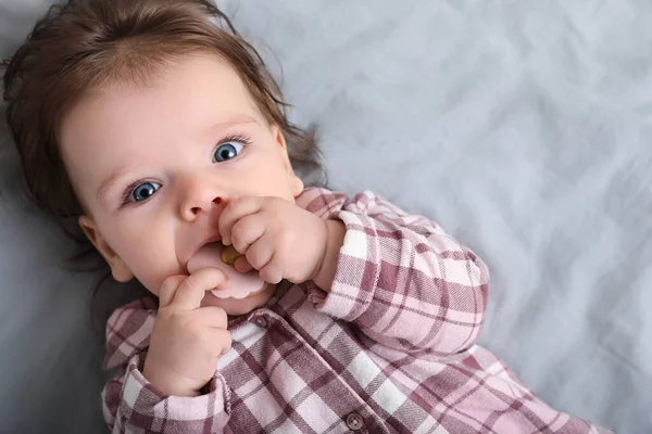 stock image Cute little baby with pacifier on bed, top view