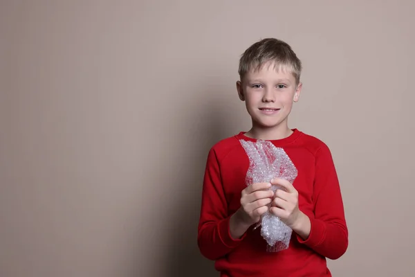 Ευτυχισμένο Αγόρι Σκάει Περιτύλιγμα Φυσαλίδων Μπεζ Φόντο Χώρος Για Κείμενο — Φωτογραφία Αρχείου