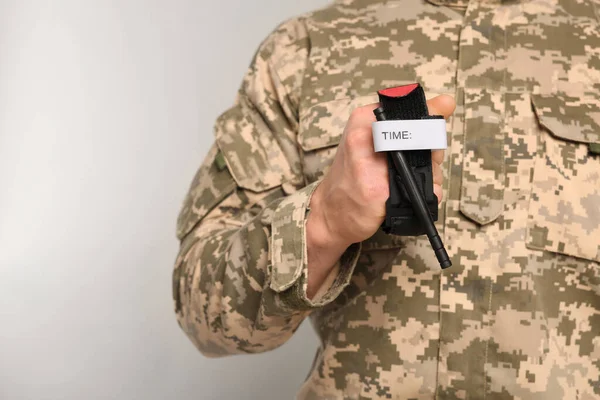 Askeri Üniformalı Asker Açık Gri Arka Planda Tıbbi Turnike Tutuyor — Stok fotoğraf