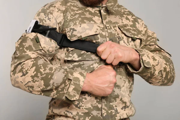 Soldado Uniforme Militar Aplicando Torniquete Médico Brazo Sobre Fondo Gris — Foto de Stock