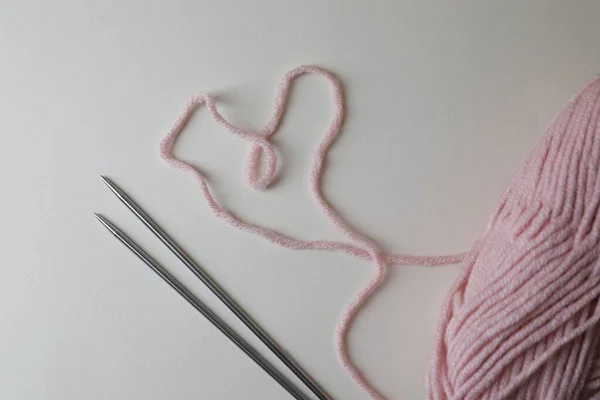 Soft pink yarn and metal knitting needles on light background, top view