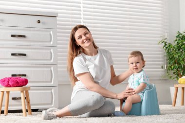Anne çocuğunu evde bebek lazımlığına oturması için eğitiyor.