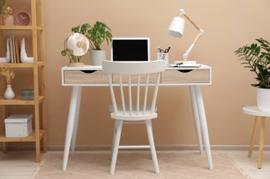 Modern dizüstü bilgisayarı olan rahat bir iş yeri ve evde rahat bir sandalye.