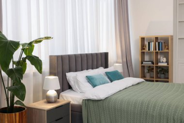 Yatak, ev bitkileri ve kitaplarla dolu rahat bir yatak.