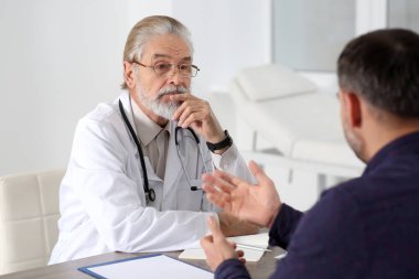 Klinikteki ahşap masada kıdemli doktora danışmanlık yapıyorum.