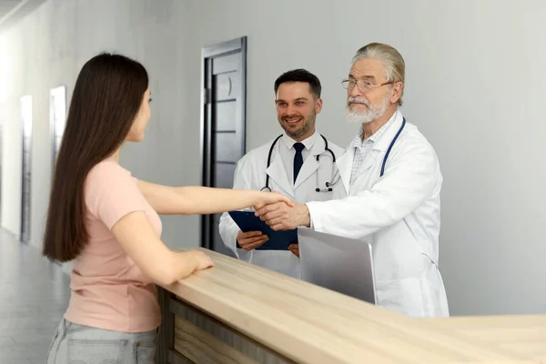 病院のホールで患者と握手シニア医師 — ストック写真