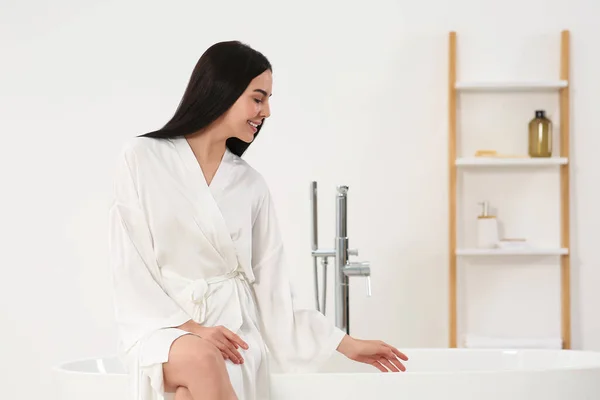 美しいです幸せな女性でスタイリッシュなバスローブでバスルームに浴槽に座って — ストック写真