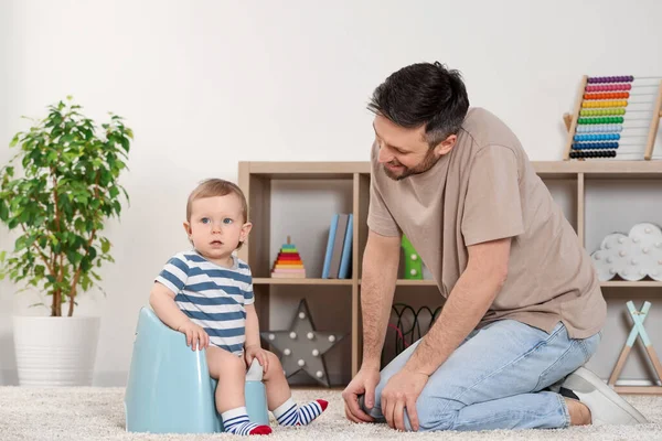 父亲训练他的孩子坐在屋里的婴儿床上 — 图库照片