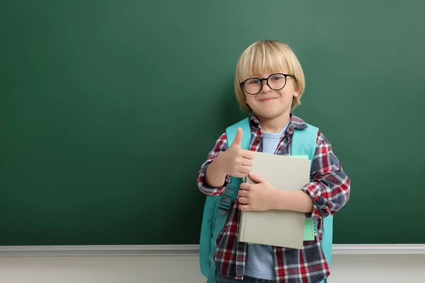黒板の近くに親指を出すノートを持つ幸せな小さな学校の子供 テキストのスペース — ストック写真
