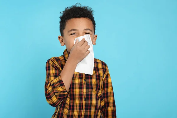 非洲裔美国男孩在绿松石背景下的组织中吹鼻涕 感冒症状 — 图库照片