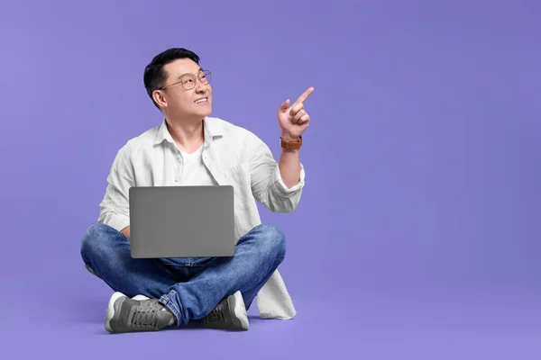 Homem Feliz Com Laptop Apontando Para Algo Fundo Lilás Espaço — Fotografia de Stock