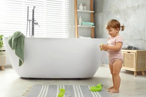 stock image Cute little girl with toys in bathroom