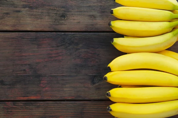 stock image Ripe yellow bananas on wooden table, flat lay. Space for text