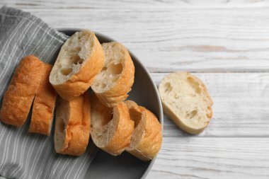 Fresh crispy ciabattas on white wooden table, flat lay