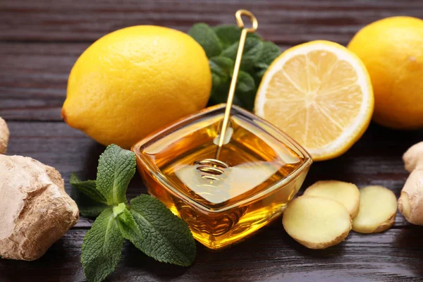 stock image Natural cough remedies. Bowl with honey, ginger, lemon and mint on wooden table, closeup