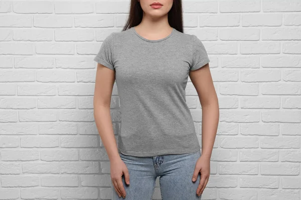 白いレンガの壁の近くにスタイリッシュなグレーのTシャツを着ている女性 クローズアップ — ストック写真
