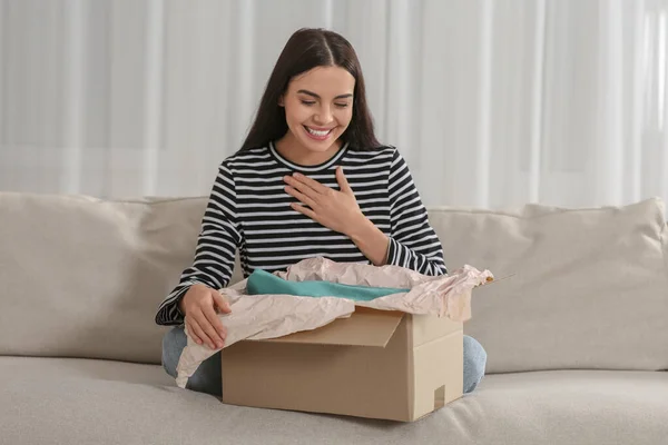 自宅でソファの上に小包と幸せな若い女性 インターネットショッピング — ストック写真