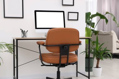 Modern işyerindeki masa ve ev bitkilerinin yanında rahat bir ofis sandalyesi