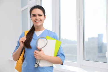 Üniversite koridorunda steteskop ve klasörleri olan zeki tıp öğrencisi.