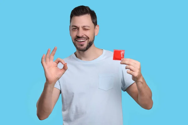 Homem Feliz Com Preservativo Mostrando Gesto Fundo Azul Claro — Fotografia de Stock