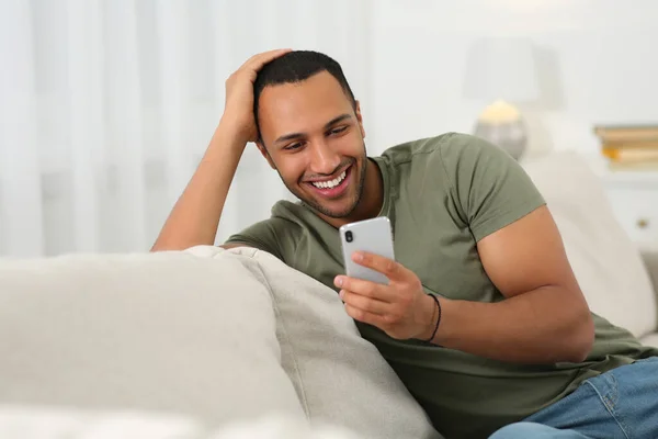 Lächelnder Afroamerikaner Mit Smartphone Auf Dem Heimischen Sofa — Stockfoto