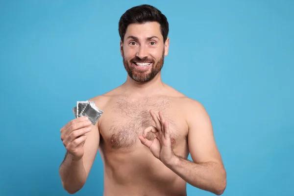 Homem Com Preservativos Mostrando Gesto Fundo Azul Claro Sexo Seguro — Fotografia de Stock