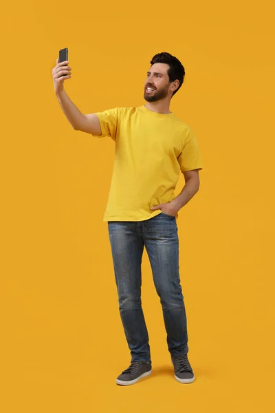 Uśmiechnięty Mężczyzna Robi Selfie Smartfonem Żółtym Tle — Zdjęcie stockowe