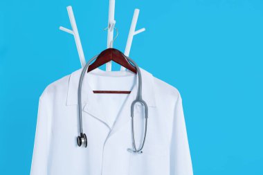 Beyaz tıbbi üniforma ve steteskop açık mavi arka planda asılı duruyor. Metin için boşluk