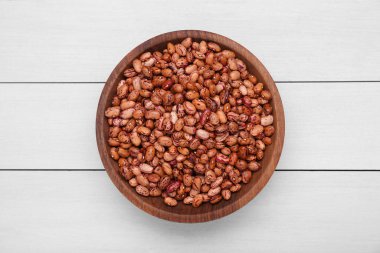 Beyaz ahşap masada kuru fasulyeli kase, üst manzara.