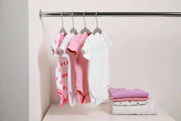 白墙附近挂着婴儿用品和成堆的衣服的吊衣架 — 图库照片