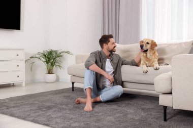 Evinde şirin Labrador Retriever 'ı olan mutlu bir adam. Metin için boşluk