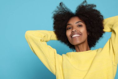 Portrait of smiling African American woman on light blue background