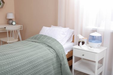 Yatak, masa ve hava nemlendiricisi olan şık bir oda.