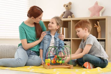 Mutlu anne ve çocuklar odada boncuk labirentiyle oynuyorlar. Matematiği eğlenerek öğreniyorum.