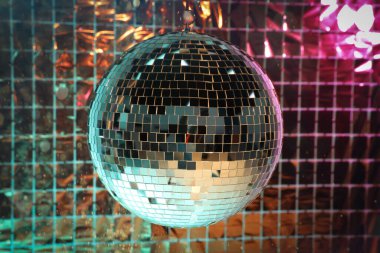 Pembe ve turkuaz ışık altında folyo parti perdesine karşı parlak disko topu