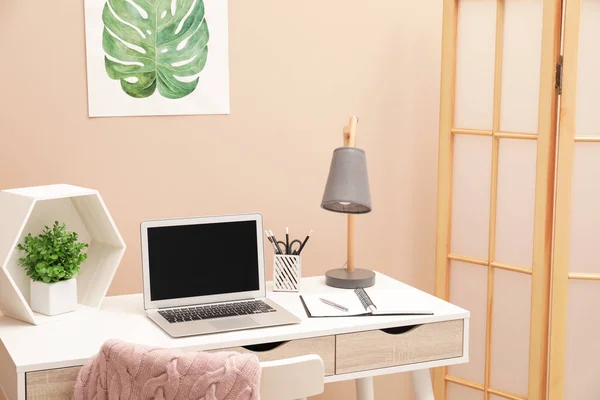 Cozy workplace with laptop and stationery on desk at home