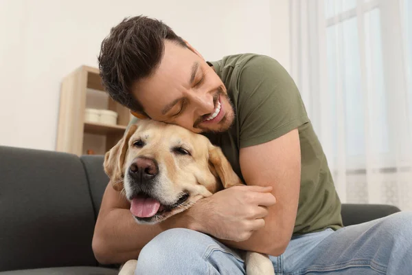 Muž Objímání Jeho Roztomilý Labrador Retrívr Pohovce Doma — Stock fotografie
