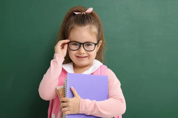 黒板の近くにノートを持つ幸せな小さな学校の子供 — ストック写真