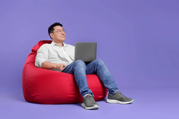 Homem Sorridente Com Laptop Sentado Cadeira Saco Feijão Contra Fundo — Fotografia de Stock