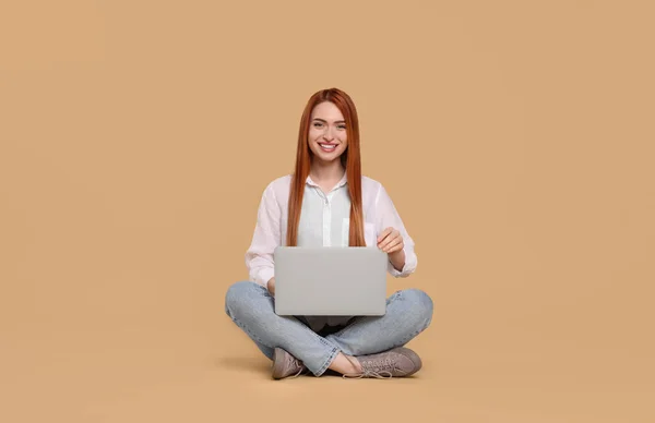 带着米色背景的笔记本电脑微笑的年轻女人 — 图库照片