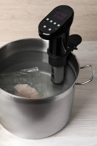 stock image Thermal immersion circulator and vacuum packed meat in pot on white wooden table. Sous vide cooking
