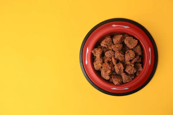 stock image Wet pet food in feeding bowl on yellow background, top view. Space for text